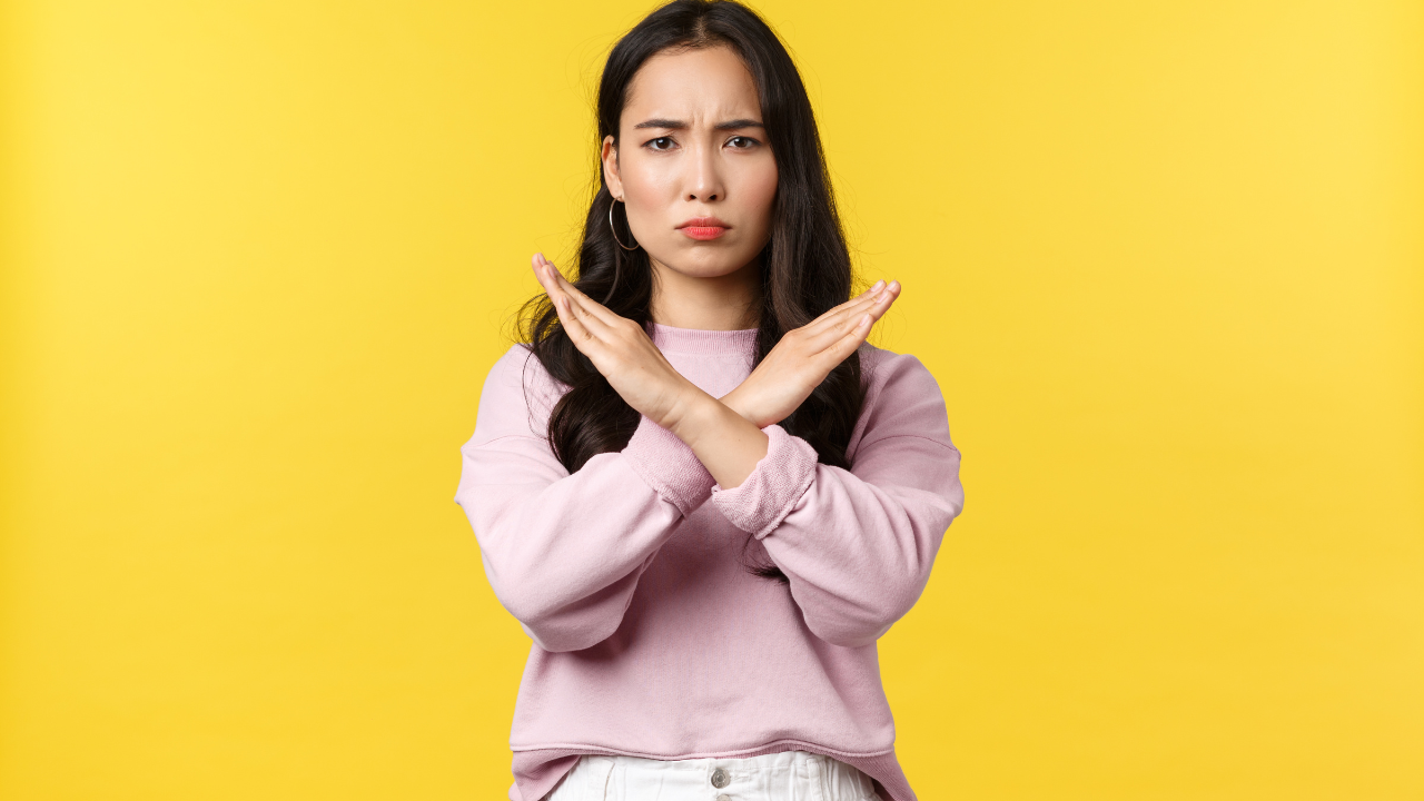 体の前に両手でバツマークを作っている女性の画像