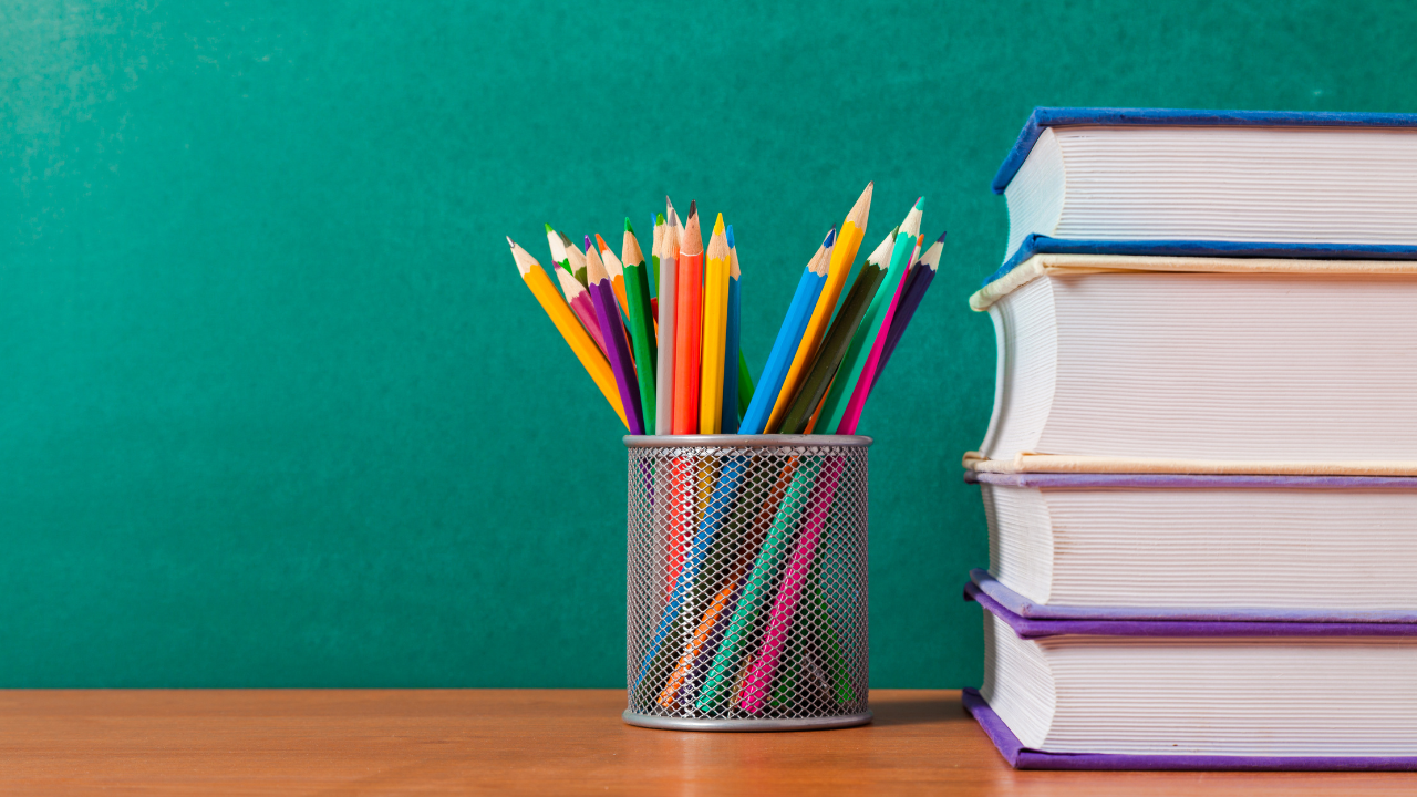 鉛筆立てに入れられた鉛筆と積まれた本の画像